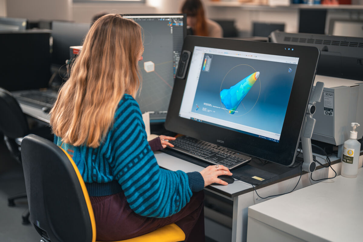 A photograph of a student using a computer pen to make adjustments to an image on their monitor